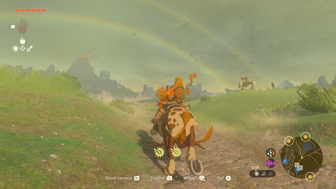 Link riding his horse across Hyrule in The Legend of Zelda: Tears of the Kingdom, featuring a lovely rainbow.