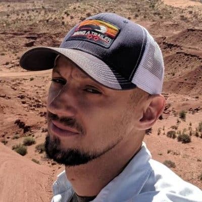 A selfie of Ryan Duffin, wearing a baseball cap in a desert landscape.