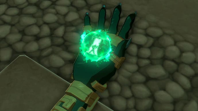 Image taken from The Legend of Zelda: Tears of the Kingdom showing a close-up of Link's hand with a glowing green orb, as the character learns the Ascend ability.