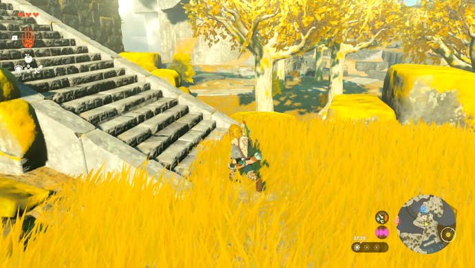 Link standing in an area with long, golden coloured grass and a staircase nearby as he begins his journey towards the In-Isa Shrine in The Legend of Zelda: Tears of the Kingdom.